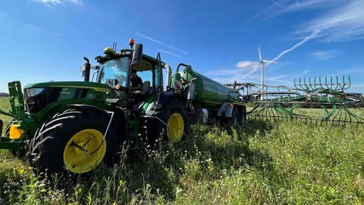 Landwirt Jan Große-Kleimann fährt mit seinem Trecker über ein grünes Feld und verteilt Gülle