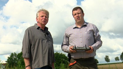 Die Landwirte Dieter Hagedorn und Stefan Schmidt stehen nebeneinander und gucken in die Luft.