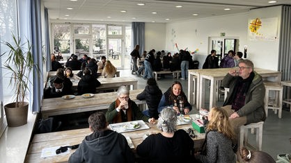 An den Tischen in der Schulmensa der Gesamtschule Weierheide in Oberhausen sitzen Schüler und Lehrer und essen