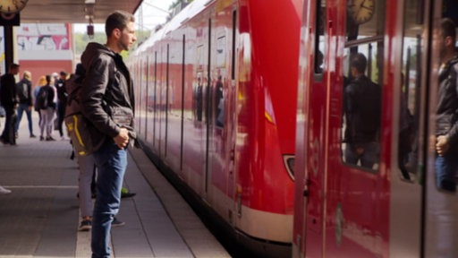 Ein Mann steht vor einer eingefahrenen S-Bahn am Bahnsteig.