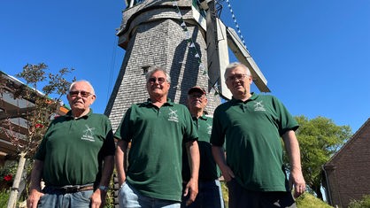 Vier Männer stehen vor einer Mühle