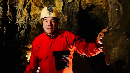 Ein Mann mit Helm und Schutzkleidung steht in einer Höhle