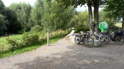 Abgestellte Fahrräder auf einem kleinen Rastplatz umgeben von grüner Natur