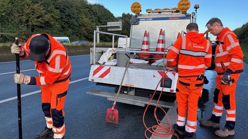 Freddy Lemkuhl und Bernd Vieth stehen am Auto auf der Autobahn