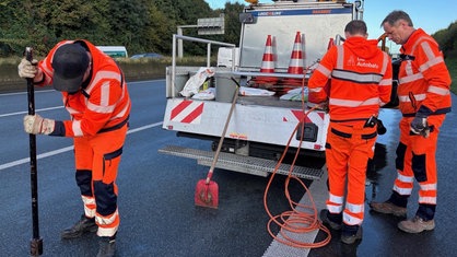 Freddy Lemkuhl und Bernd Vieth stehen am Auto auf der Autobahn