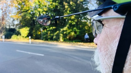 Max Holz trägt einen Fahrradhelm, der mit einem Rückspiegel ausgestattet ist