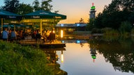 Menschen sitzen in der Abendsonne in einem Biergarten am Grugapark in Essen