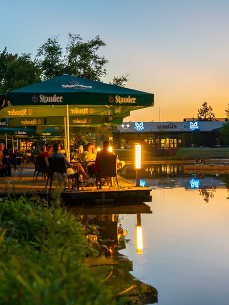 Menschen sitzen in der Abendsonne in einem Biergarten am Grugapark in Essen