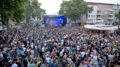 eine Menschenmenge in der Innenstadt vor einer Musikbühne