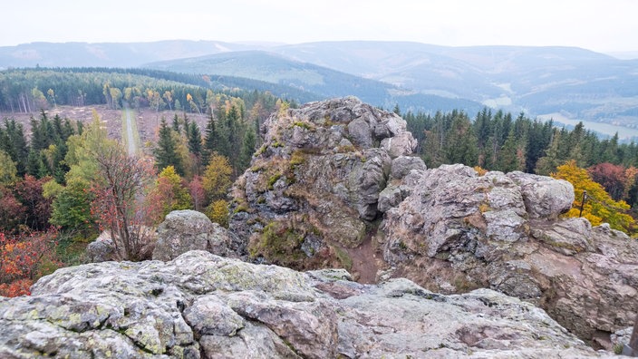 Sicht von oben an der Klippe einer Gesteinsformation mit Blick über ein Tal. 