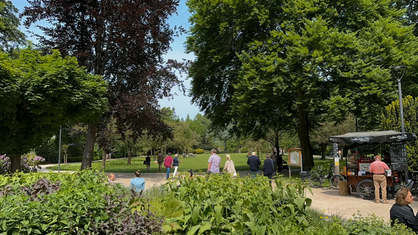 Im Bunten Garten in Mönchengladbach laufen Leute zwischen grünen Wiesen und Bäumen entlang