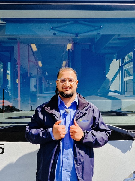 Serhat Yeschil steht vor einem Bus und hält seine Daumen hoch