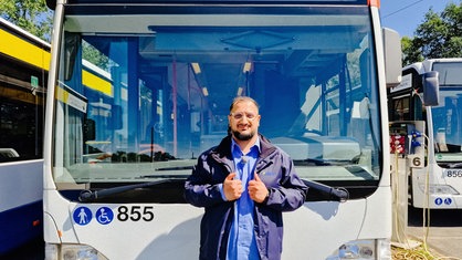 Serhat Yeschil steht vor einem Bus und hält seine Daumen hoch