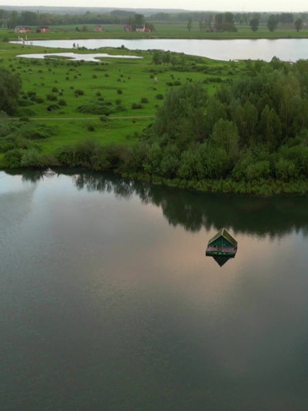 Auf einem See umringt von grünen Wiesen und Bäumen schwimmt ein Floß.
