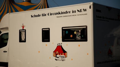 Ein weißes Wohnmobil mit der Aufschrift "Schule für Circuskinder in NRW"