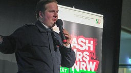 Lukas Ritgens auf der Bühne mit einem Mikrofon in der Hand