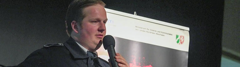Lukas Ritgens auf der Bühne mit einem Mikrofon in der Hand