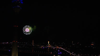 Hinter dem Rheinturm in Düsseldorf ist Feuerwerk zu sehen