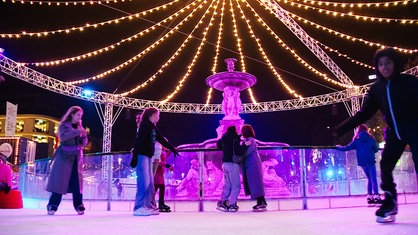 Menschen auf einer bunt beleuchteten Eisbahn