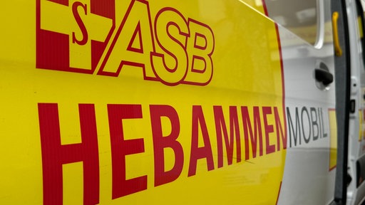 Gelber Hintergrund mit roter Aufschrift auf der steht: ASB-Hebammenmobil