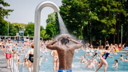 Ein gut besuchtes Freibad, im Vordergrund eine Dusche