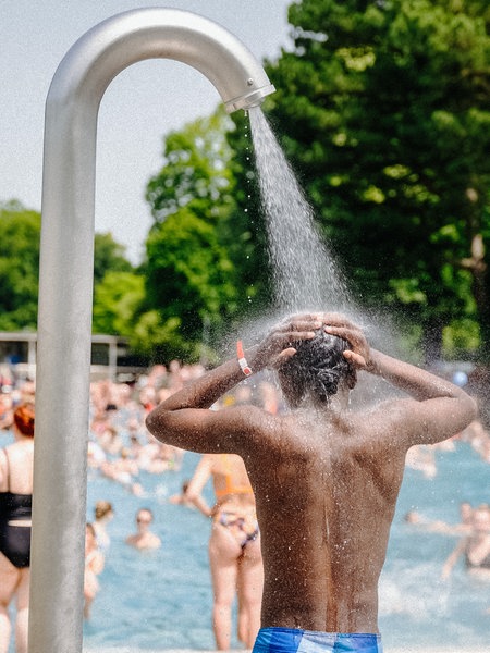 Ein gut besuchtes Freibad, im Vordergrund eine Dusche