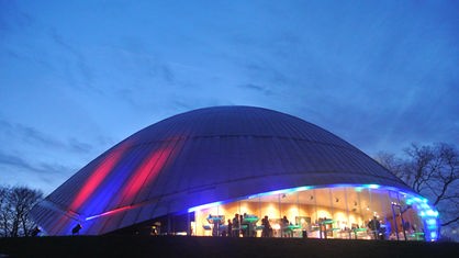 Die bunt beleuchtete Kuppel des Bochumer Planetariums von außen am Abend