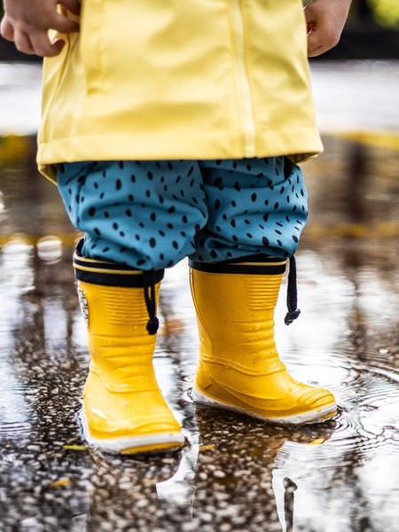 Ein Kind springt mit Gummistiefeln in eine Pfütze