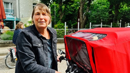 Eine Frau, die einen Fahrradlenker festhält und in die Kamera schaut.