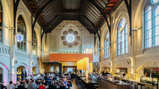 Eine Bar und viele Tische mit Menschen stehen in einer Kirche