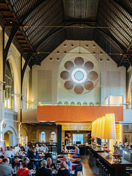 Eine Bar und viele Tische mit Menschen stehen in einer Kirche