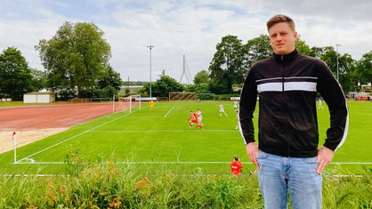 Ein junger Mann steht an einem Fußballplatz