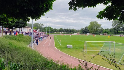 Ein Sportplatz mit Zuschauern, Fußballtoren und einer 400 Meter Bahn