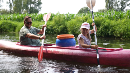 Ein Mädchen und ihr Vater paddelnd auf einem Fluss.