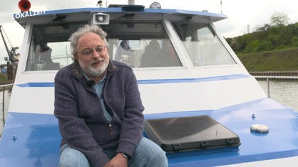 Pfarrer Frank Wessel sitzt vorne auf dem Deck eines Bootes.
