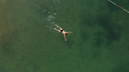 Luftaufnahme, eine Frau schwimmt in einem See