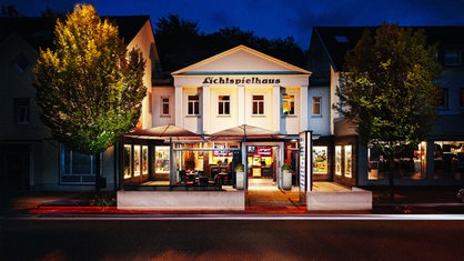 Das Lichtspielhaus in Lennestadt am Abend flankiert von zwei Bäumen, davor der kleine Biergarten 