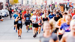 Etliche Personen joggen dicht gedrängt auf einer asphaltierten Straße.