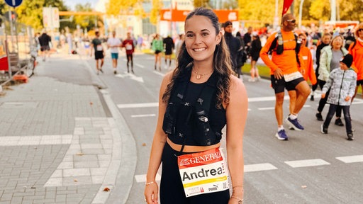 Eine junge Frau steht am Zieleinlauf des Köln-Marathons.