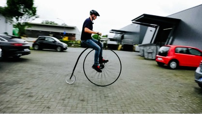 Klaus Lenfort sitzt auf seinem Hochrad und hat einen Helm auf