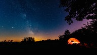 Ein erleuchtetes Zelt steht im Naturpark Nordeifel