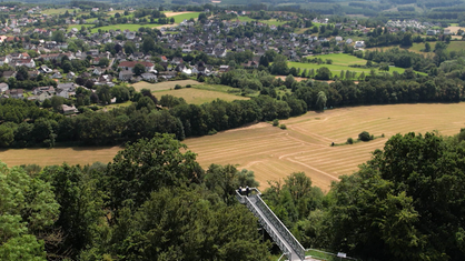 Drohnenflug über den Skywalk Möhnetal im Hintergrund die umliegende Landschaft.