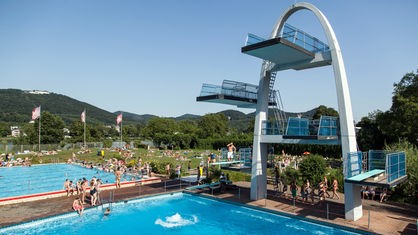 Der Sprunggturm des Panoramabads direkt an den Schwimmbecken. Um ihn herum sind zahlreiche Badegäste zu sehen.
