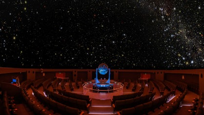 Das Planetarium in Bochum von innen, in der Mitte steht der Sternenprojektor, an der Kuppel leuchten Sterne