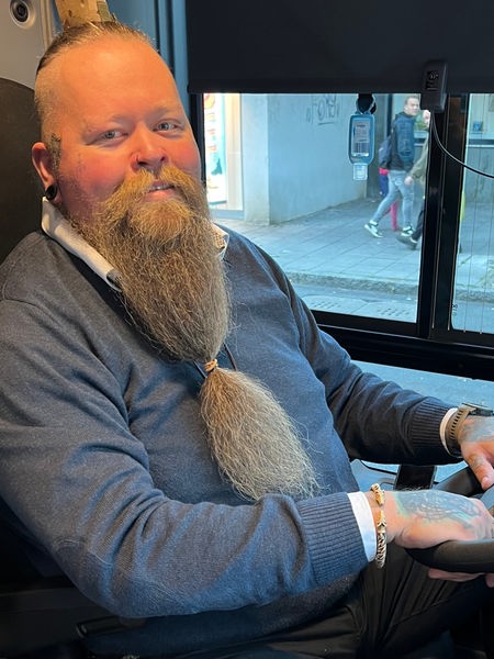 Busfahrer Alex Menschel sitzt am Steuer und lächelt 