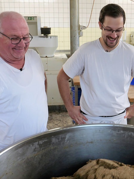 Zwei Männer stehen an einer Brotmaschine