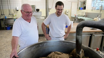 Zwei Männer stehen an einer Brotmaschine