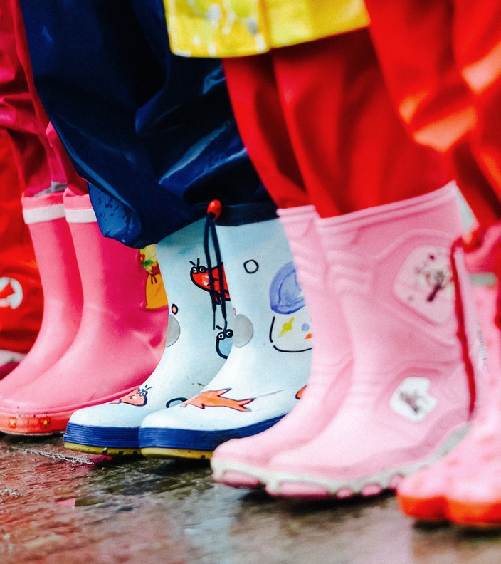 Die Beine von fünf Kindern in Regenkleidung nebeneinander.