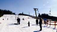 Familien stehen und rodeln am Rodellift des Sahnehangs in Winterberg.