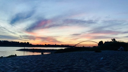 Der Abendhimmel an den Sandbuchten. Wenige Wolken sind zu sehen und die Sonne taucht die Szenerie in ein orange, violettes Licht.